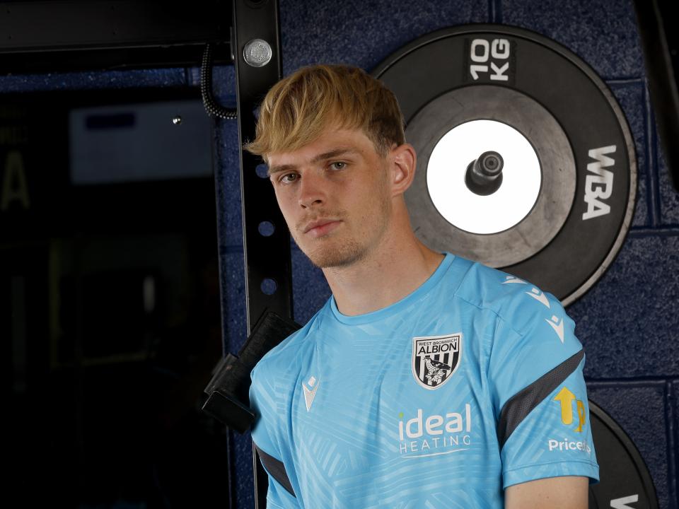 Toby Collyer looking at the camera while stood in front of weights in the gym