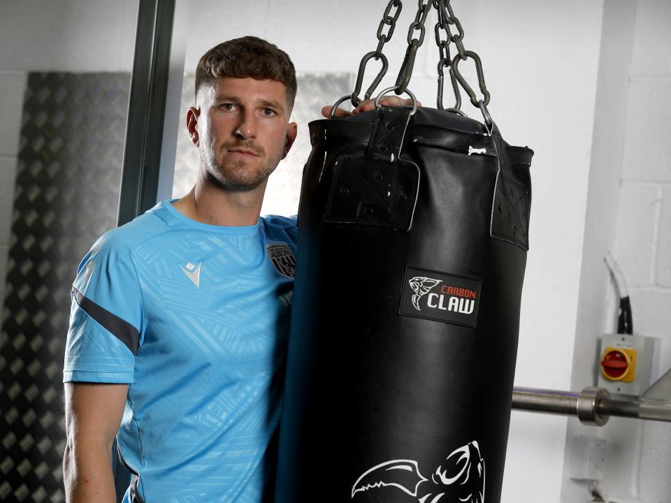 Chris Mepham leaning on a punch bag in the gym looking at the camera