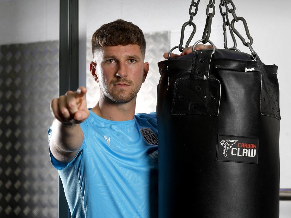 Chris Mepham pointing and looking at the camera while leaning on a punch bag in the gym