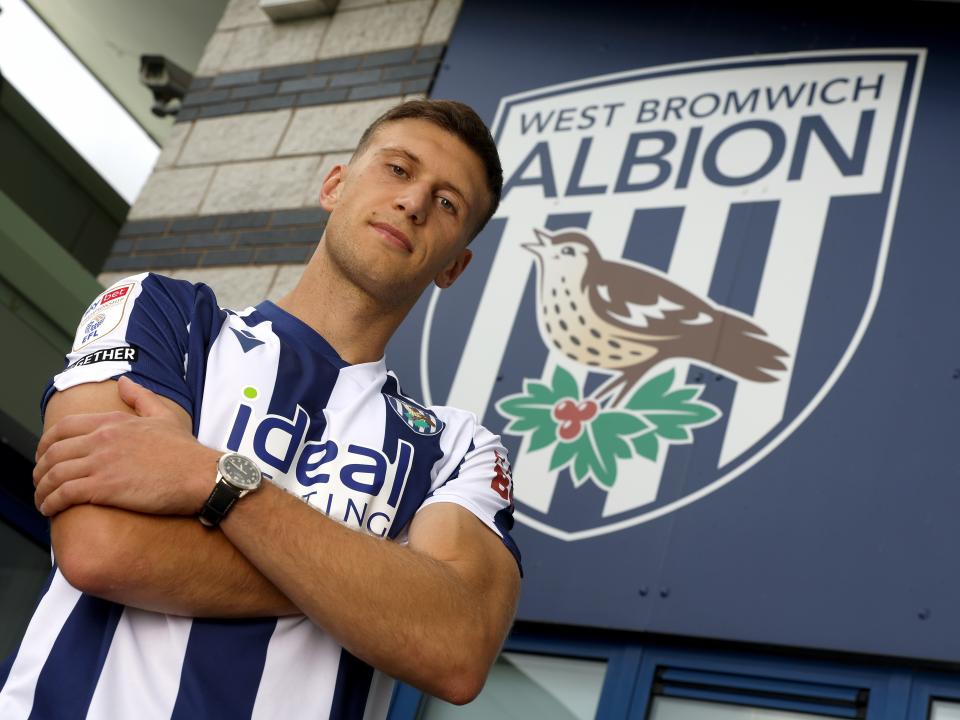 Krystian Bielik looking at the camera while stood in a home shirt with his arms folded