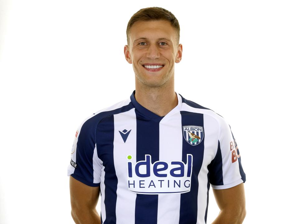 Krystian Bielik smiling at the camera in the home kit 