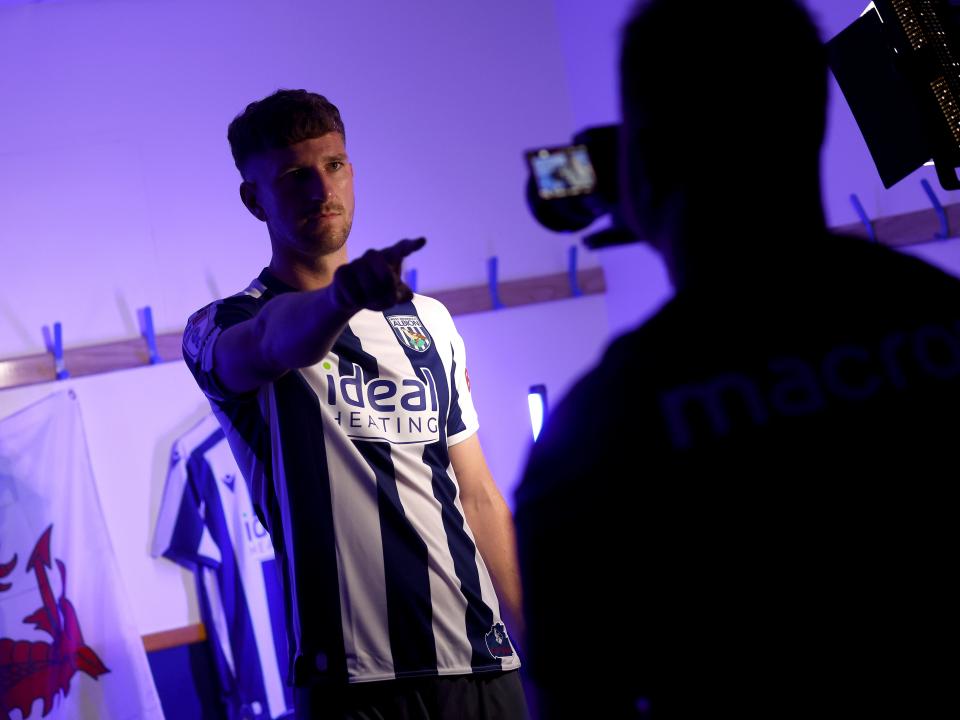 Chris Mepham pointing at a camera while being stood in a home shirt 