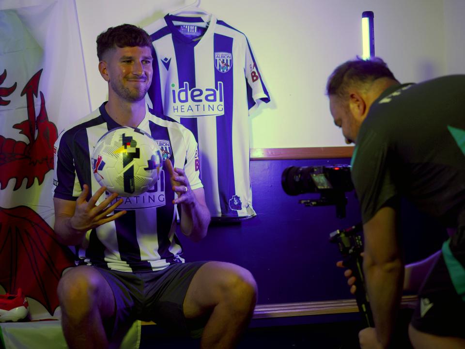 Chris Mepham smiling while sat on a bench in home kit 