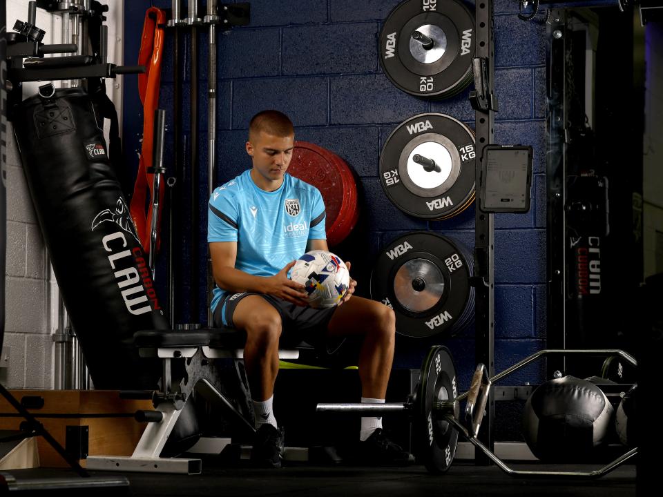 Alfie Gilchrist sat in the gym surrounded by weights holding a ball