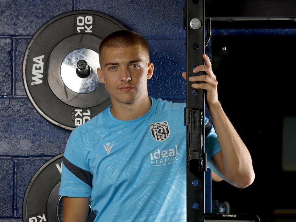 Alfie Gilchrist leaning up against a frame in the gym smiling at the camera 