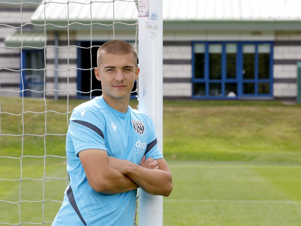 Alfie Gilchrist with his arms folded leaning up against a goal post