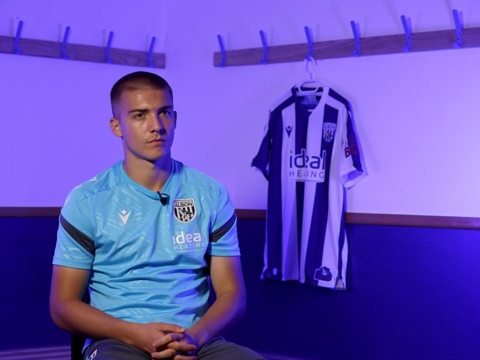 Alfie Gilchrist speaking to WBA TV with a WBA home shirt in the background hanging up
