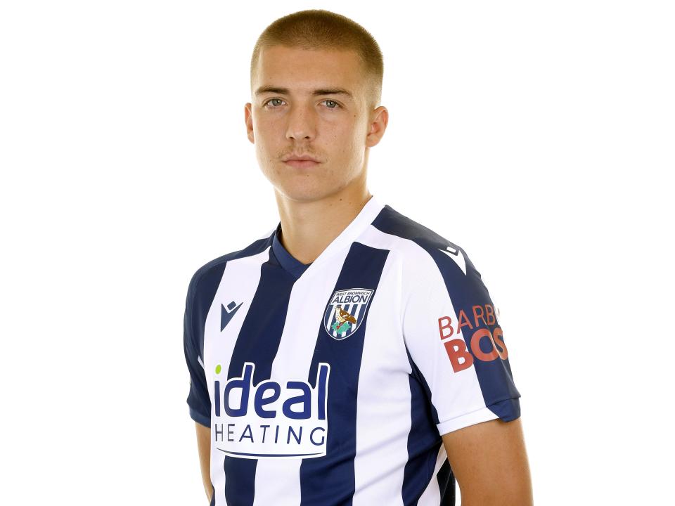 Alfie Gilchrist looking at the camera while stood in a home shirt