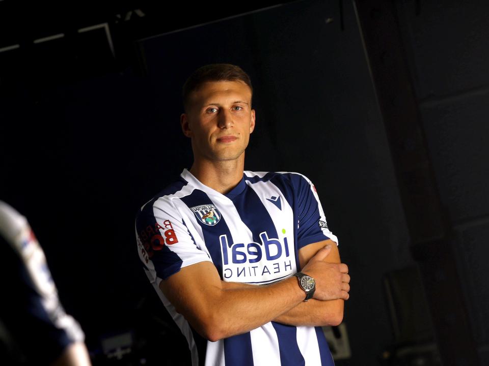 Krystian Bielik looking at the camera with arms folded in a home shirt 