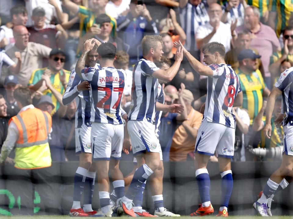 Albion players celebrate with Isaac Price after his goal at Wrexham with WBA fans in the background 