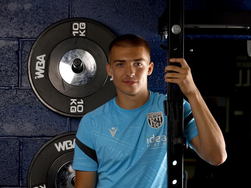 Alfie Gilchrist smiling at the camera while leaning against a bar in the gym
