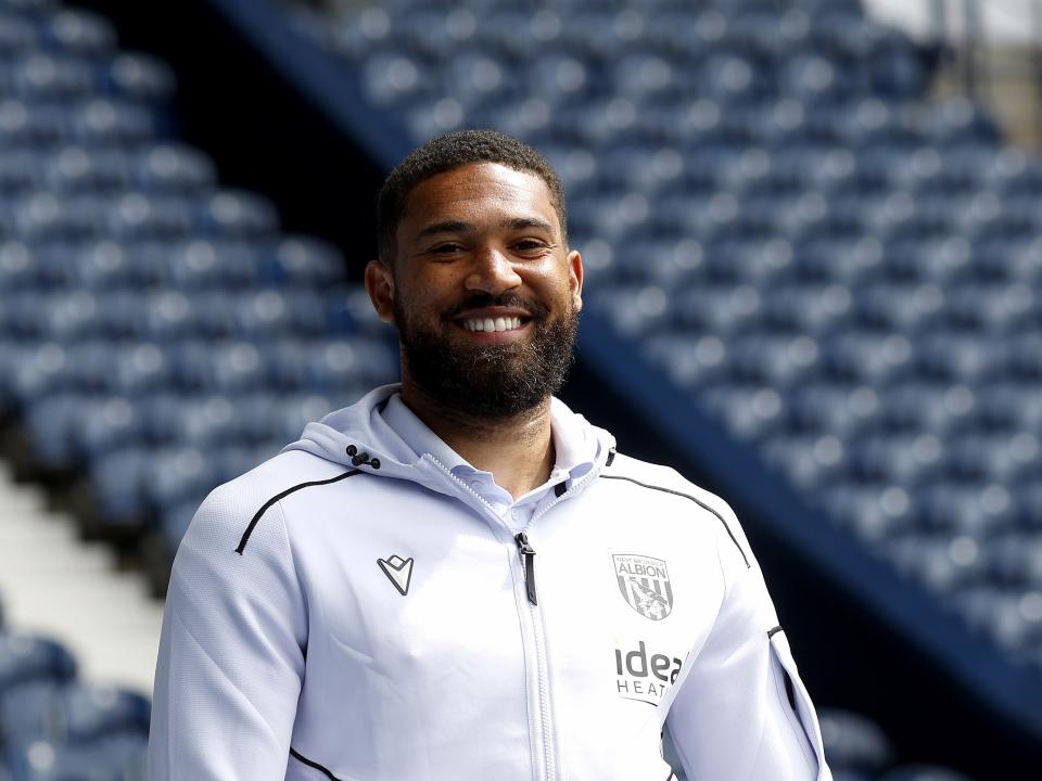 George Campbell in a white WBA tracksuit smiling and looking at the camera 
