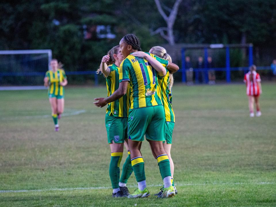 Amya Hammond-McLean celebrating a goal in the yellow and green away kit