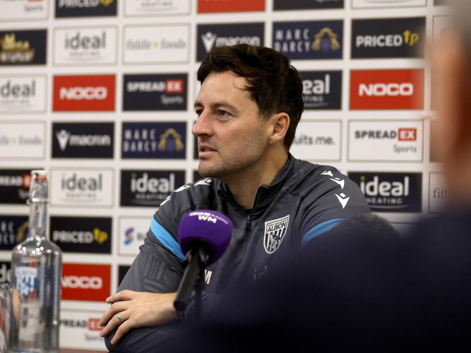 Ryan Mason speaking to press in front of a sponsors board 