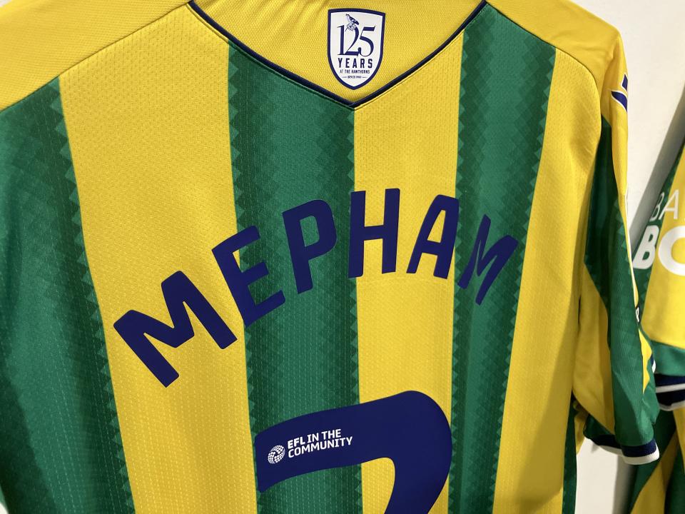 Chris Mepham's name on the back of a yellow and green away shirt 