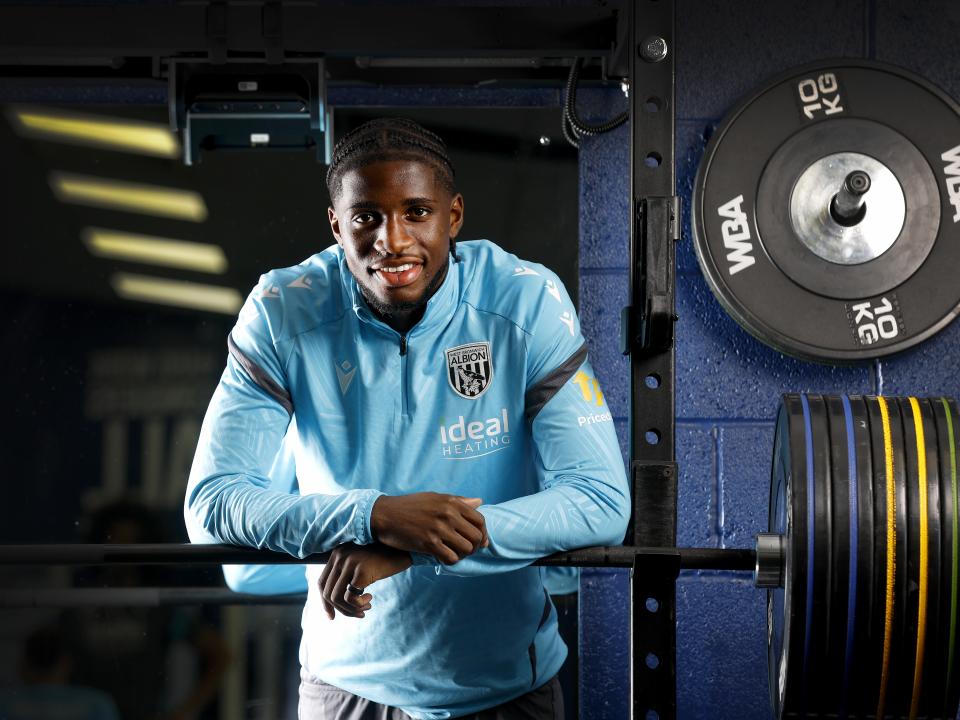 Samuel Iling-Junior smiling at the camera while leaning on a bar in the gym