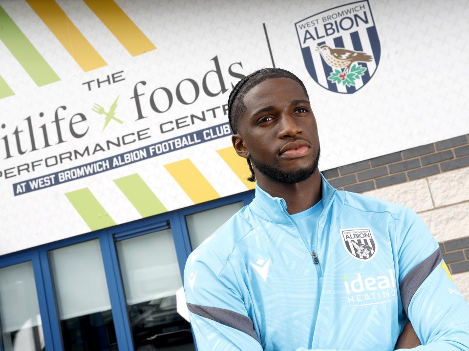 Samuel Iling-Junior looking at the camera while stood in front of branding outside the training ground