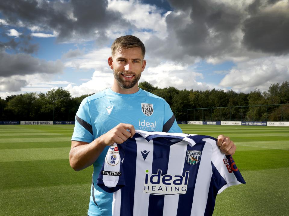 Charlie Taylor smiling at the camera while holding up a home WBA shirt