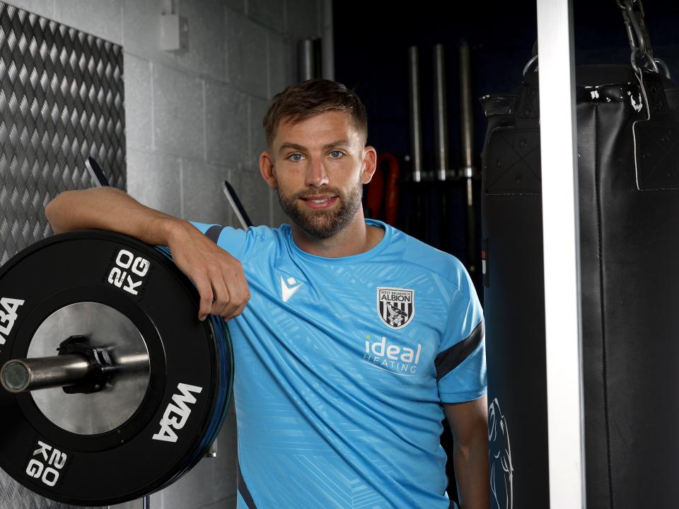 Charlie Taylor smiling at the camera while leaning on weights in the gym