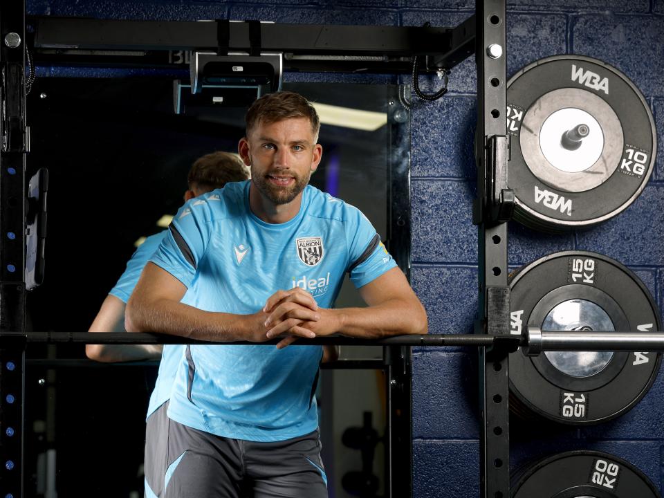 Charlie Taylor smiling at the camera while leaning on a bar in the gym