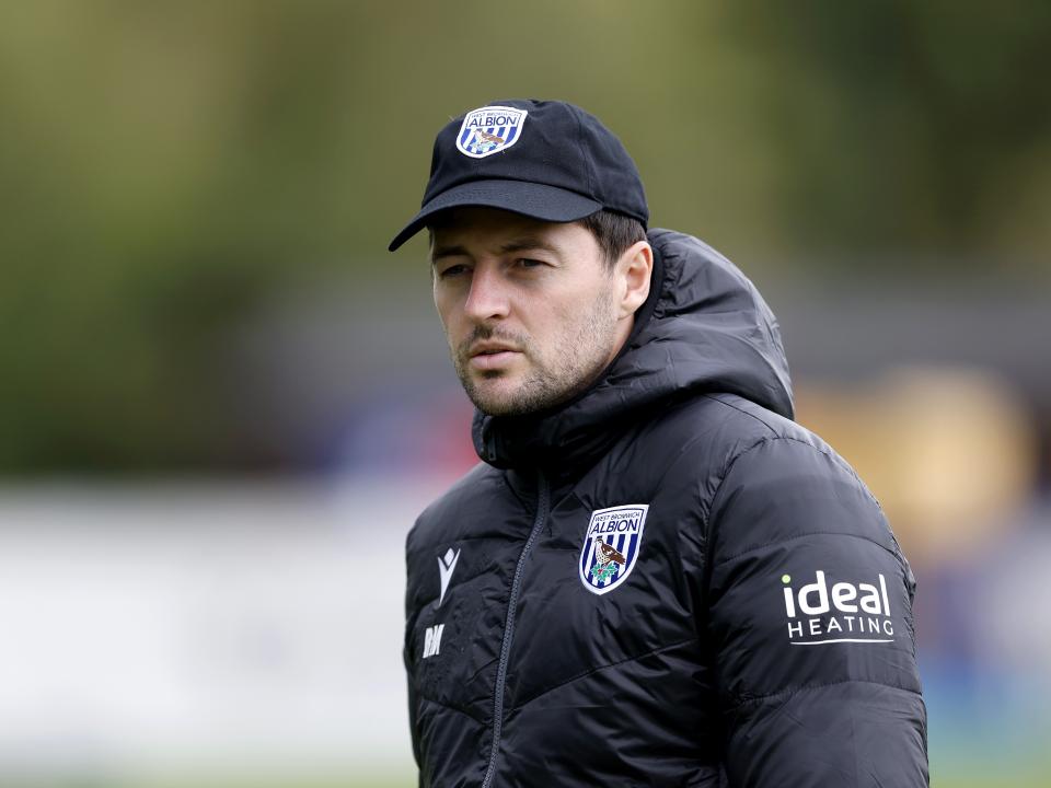 Ryan Mason watching training while wearing a coat and cap