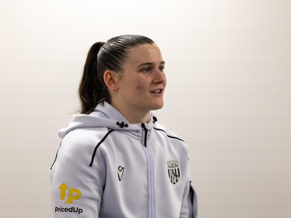 Charlotte Clarke being interviewed after a game in her white tracksuit 