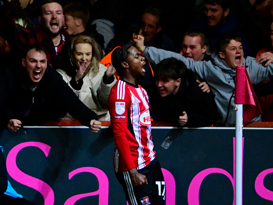 Akeel Higgins celebrates scoring for Exeter with supporters in the background 