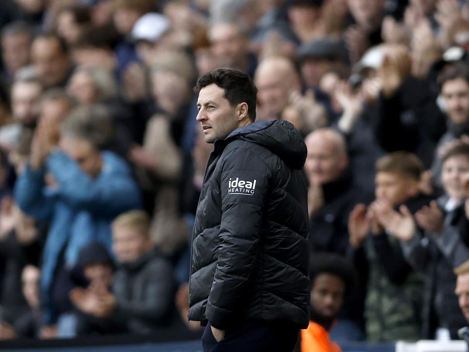 Ryan Mason wearing a coat on the side of the pitch watching a game 