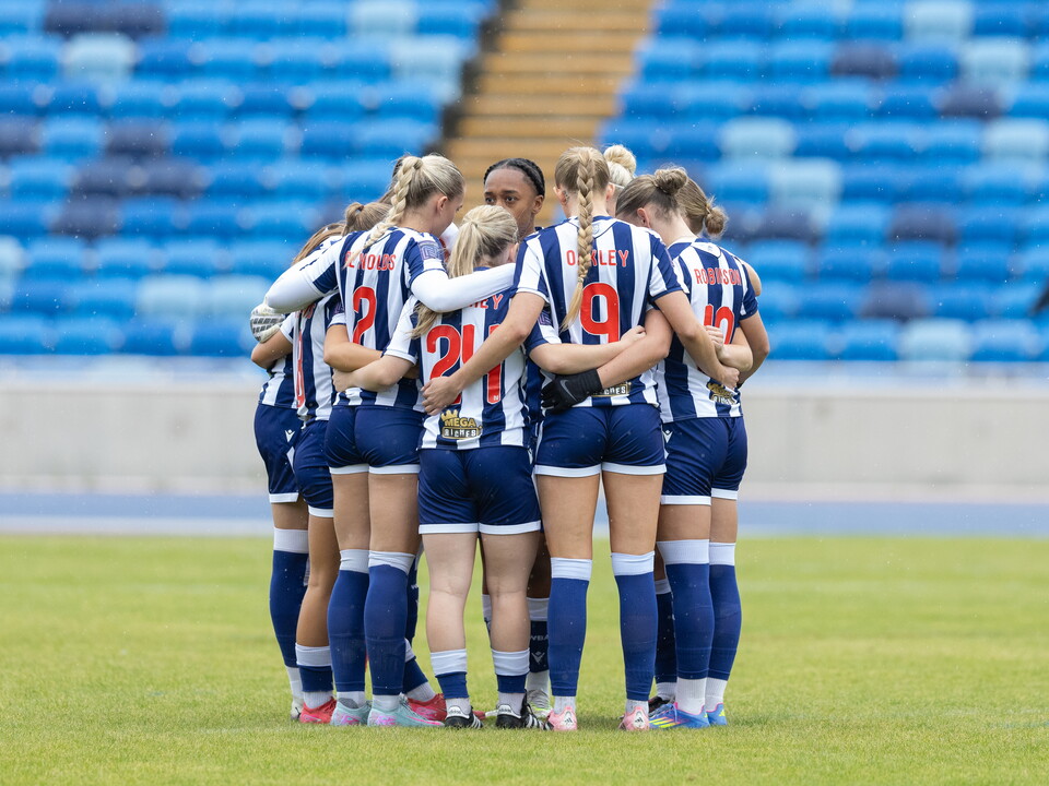 A phot of Albion women in a huddle on a game day. 