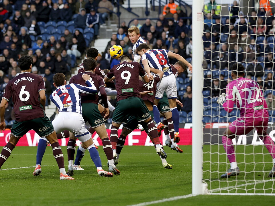 Several players jumping to win a header in the penalty area during the game between WBA and Swansea