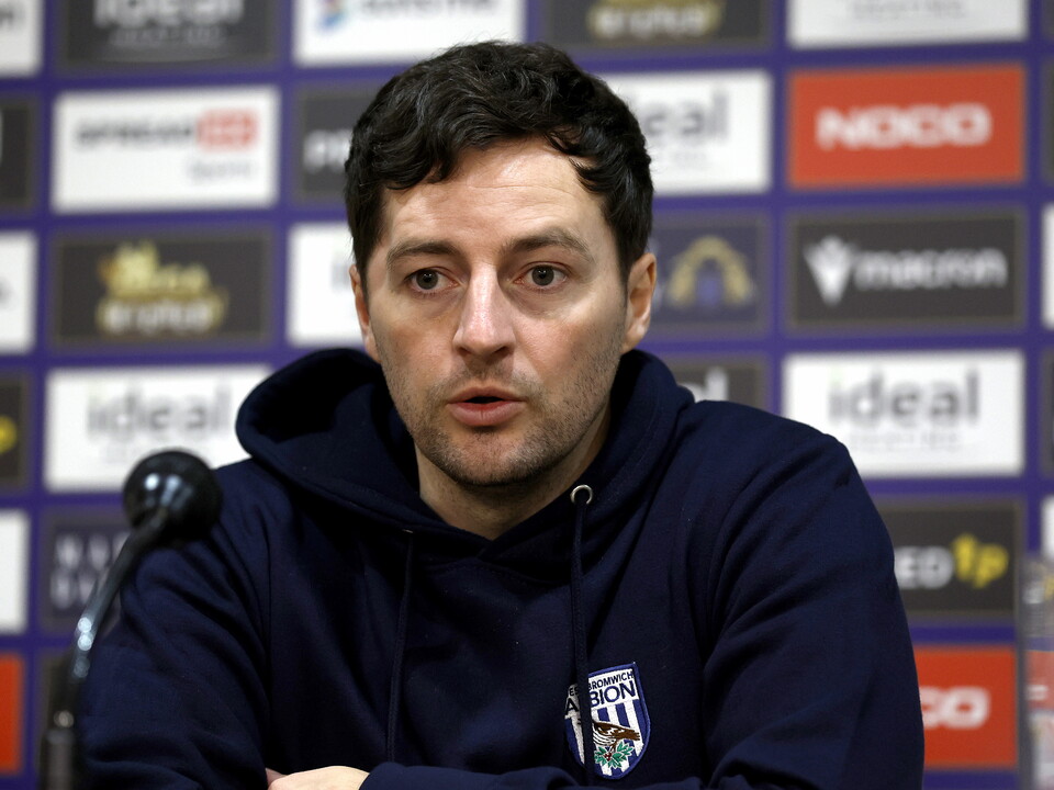 Ryan Mason speaking to the media in front of a sponsor board