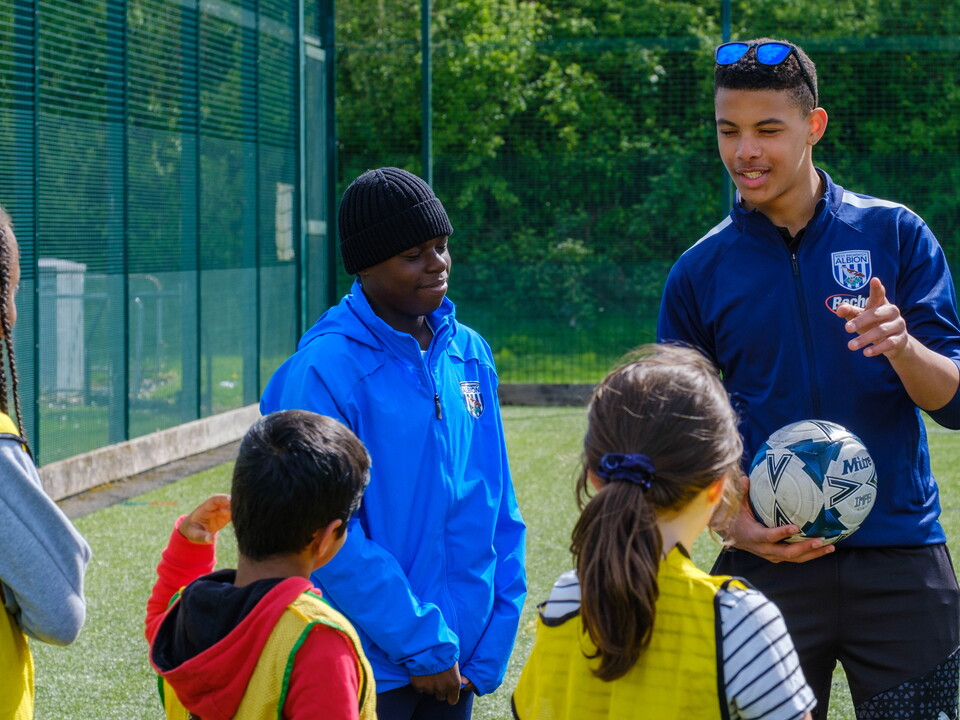 Two volunteers speaking with a small group of children