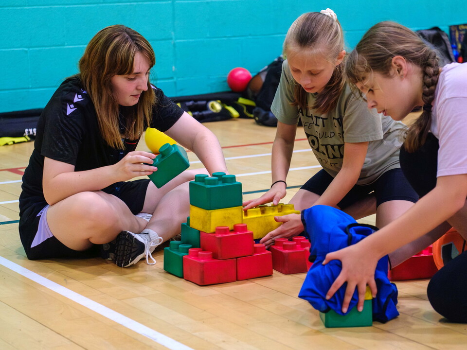 Volunteer building blocks with two young female participants.