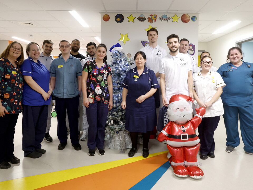 Several WBA players posing for a photo with NHS staff members on a ward at the Midlands Met hospital 