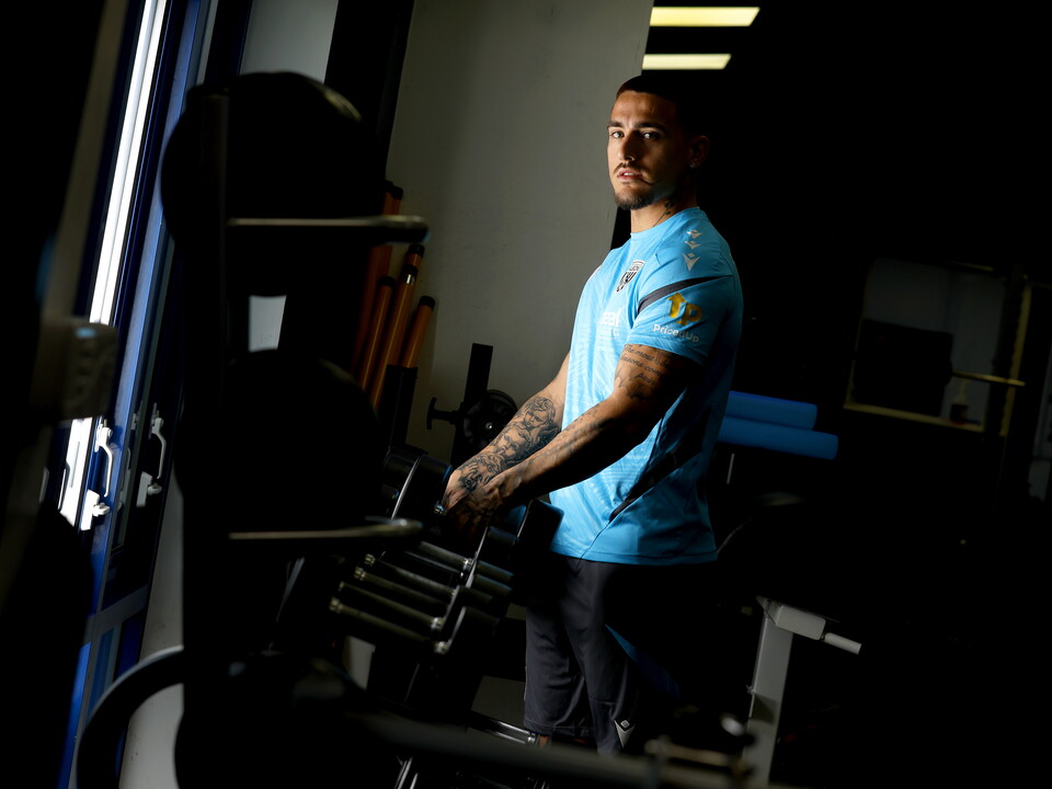 Danny Imray smiling at the camera while leaning against equipment in the gym