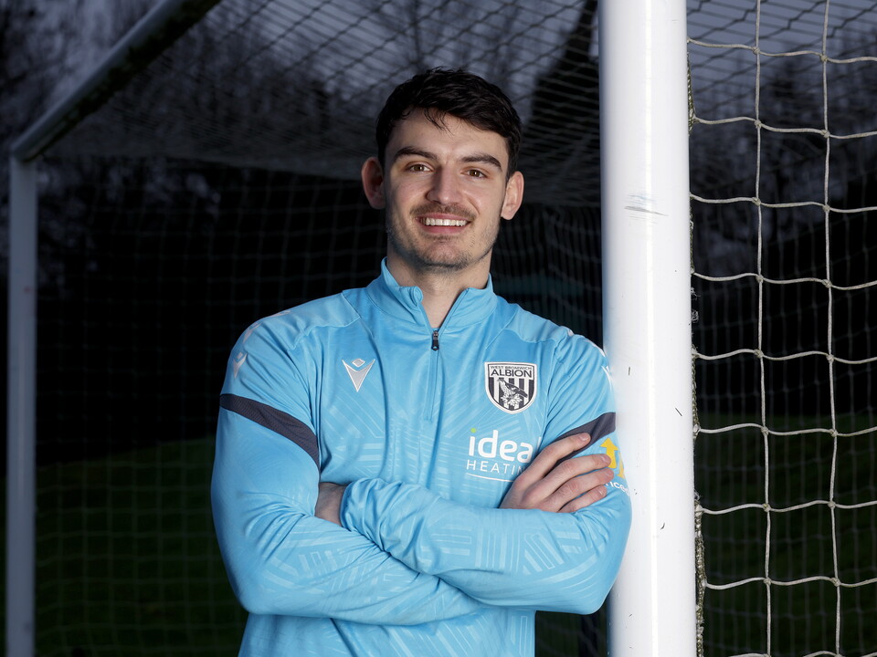 Max O'Leary smiling at the camera while leaning against a goal post