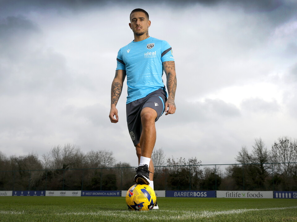 Danny Imray stood with one foot on a ball on the training pitch while looking at the camera 