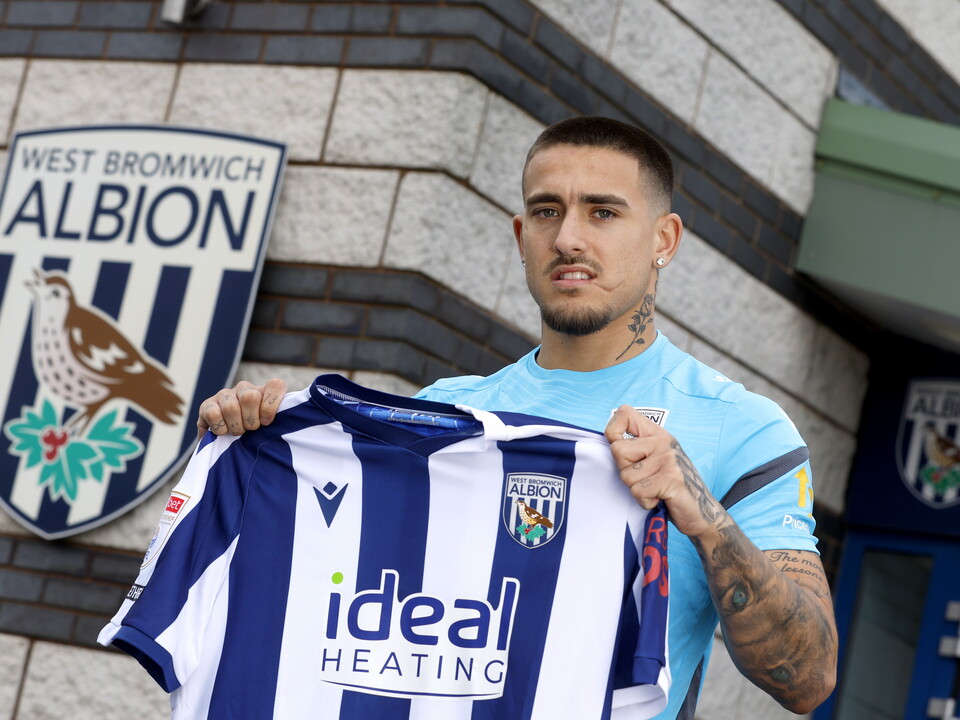 Danny Imray smiling at the camera while holding up a home WBA shirt 