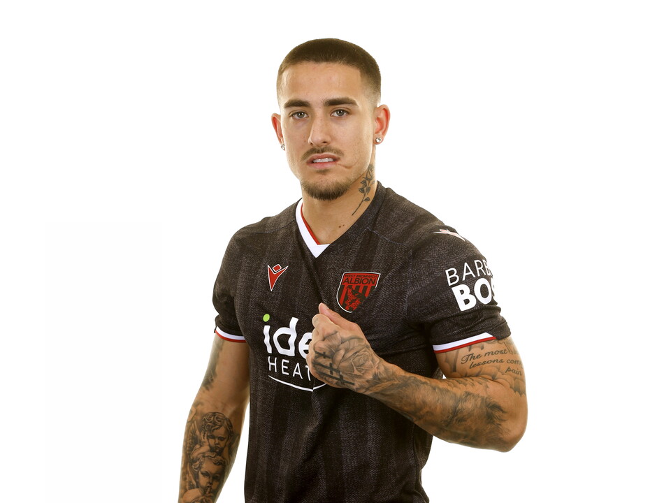 Danny Imray smiling at the camera while stood in front of a white background in a black away WBA shirt