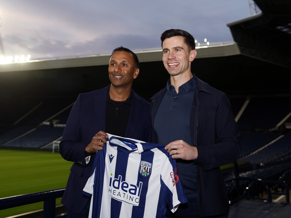 Eric Ramsay and Shilen Patel smiling at the camera and holding up a home WBA shirt at The Hawthorns