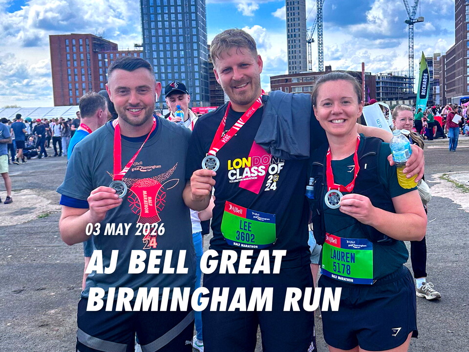 Three people are posing for a photo after completing a race. They are wearing medals and holding water bottles.