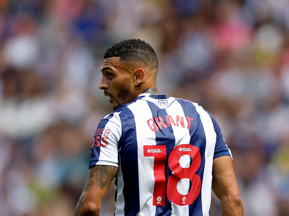 Karlan Grant facing away from camera in the home kit during a game