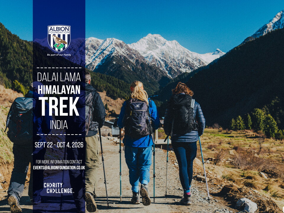 Four hikers walking the path with the Himalayan Mountains in the distance