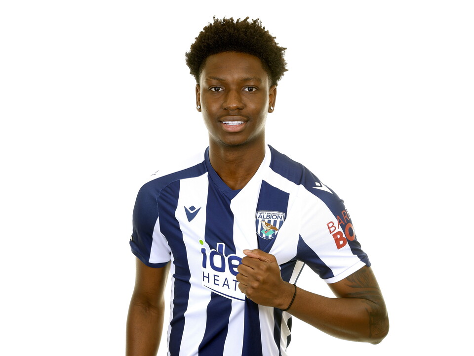 Jamaldeen Jimoh-Aloba smiling at the camera while stood in front of a white background in the home kit