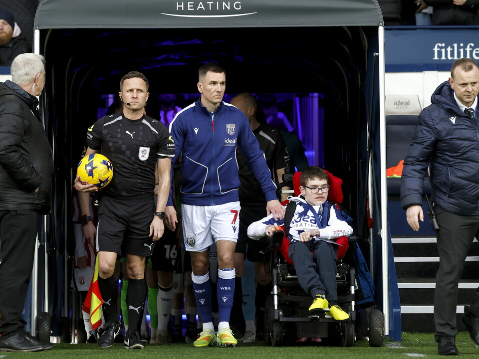 Jed Wallace walking out of the tunnel with a disabled WBA fan