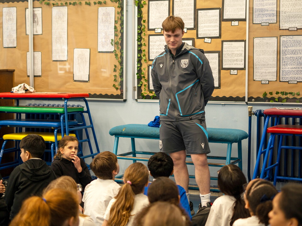 Apprentice standing in front of a group of school children.