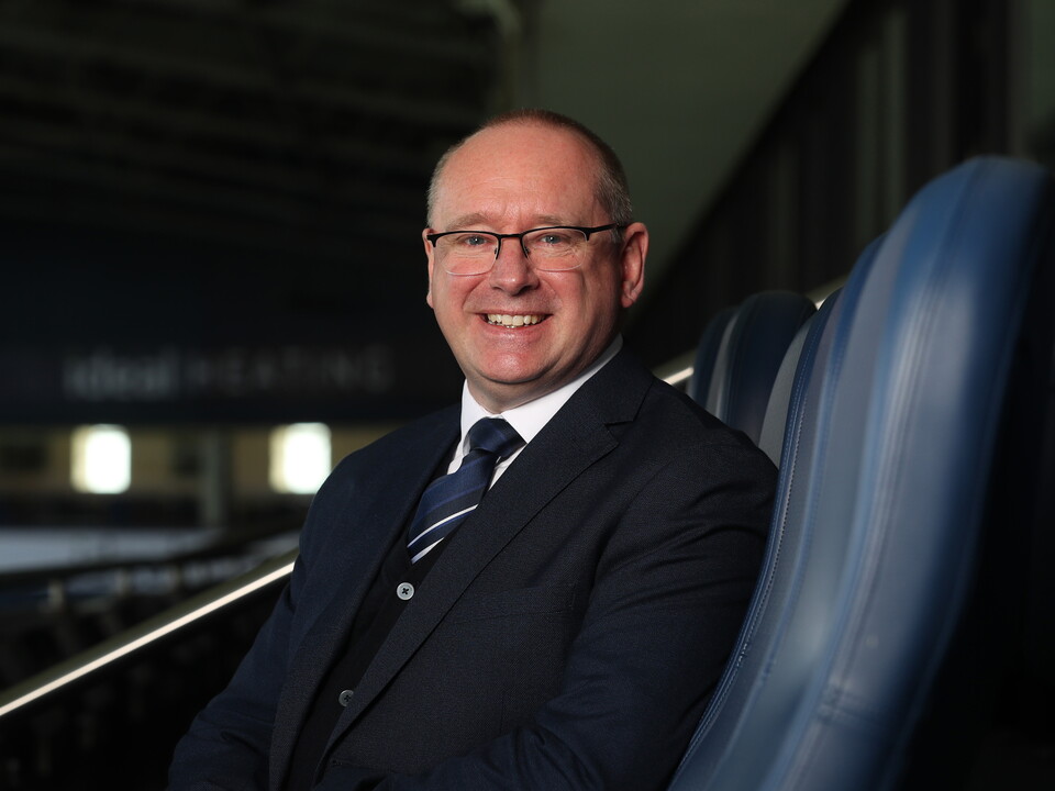 Mark Miles smiling at the camera while sat in a seat at The Hawthorns
