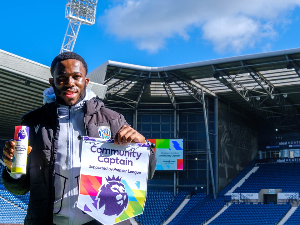 Kadeem Jordan holding the Premier League Community Captain trophy and pendant.
