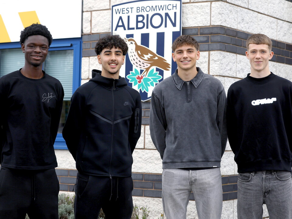Abdul Abudu, Adam Letlat, Charlie Blackshields and Ryan Colesby smile at the camera in front of the training ground 