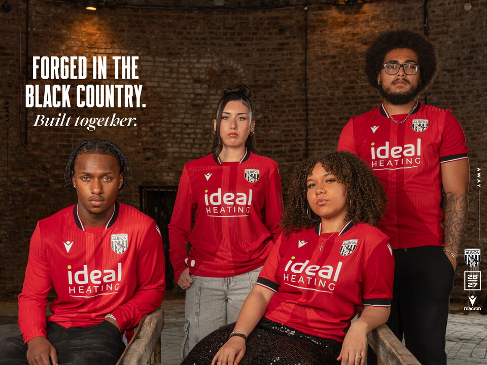Four individuals posing for a photo in the new red away kit 